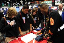 Gunnery Sgt. Jason Knuckles, the musician technical assistant for the 9th Marine Corps District, speaks to a group of high school students at a Marine Corps Music Program booth, during the 2011 Midwest Clinic, Dec. 14. The Midwest Clinic is an annual event to promote music education.